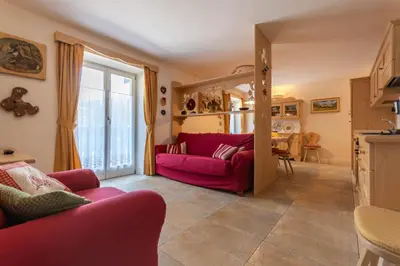 a living room with a red couch and a table at Casa Rosi in Pozza di Fassa