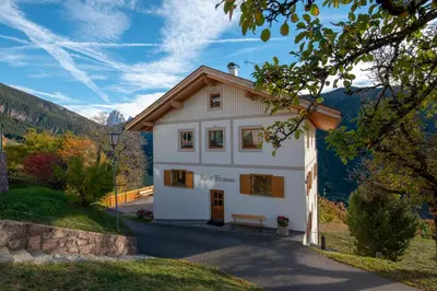 a house in the mountains with a bench in front at Appartment Kirch Neuhaus in Laion