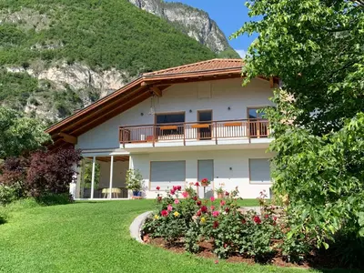 a house with a balcony and flowers in a yard at Haus Greti in Magrè allʼ Adige