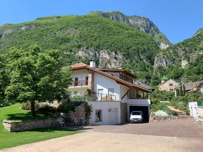 a house with a car parked in front of a mountain at Haus Greti in Magrè allʼ Adige