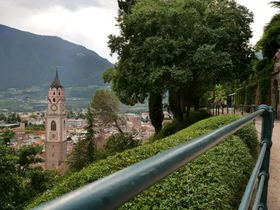 a building with a clock tower on a hill at Apartments Sabine G in Merano
