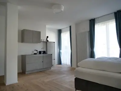 a bedroom with a bed and a cabinet and windows at Apartments Sabine G in Merano