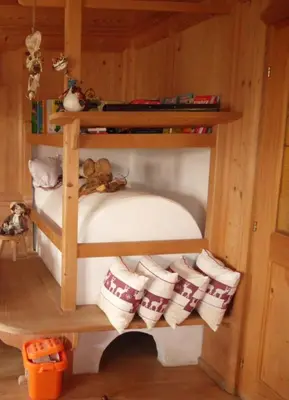 a wooden bunk bed with pillows and a teddy bear at B&B Brunnerhof in Feldthurns