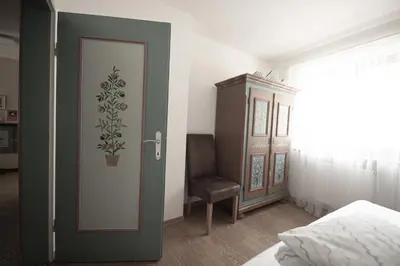 a bedroom with a door and a chair next to a bed at Village Charme in Molini di Tures