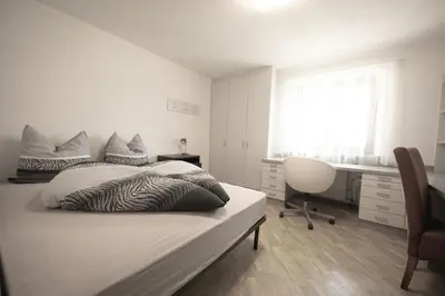a white bedroom with a bed and a desk at Village Charme in Molini di Tures