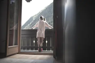 a girl standing on a balcony looking out the window at Village Charme in Molini di Tures