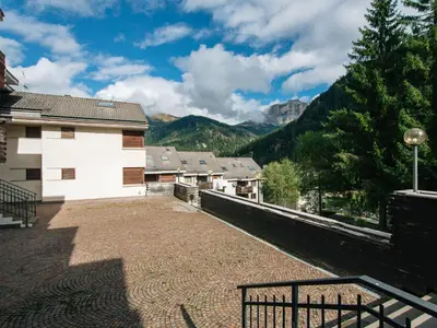 a village covered in snow with mountains in the background at Apartment Enrosadira-7 by Interhome in Alba di Canazei