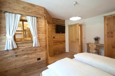 a bedroom with wooden walls and a bed and a window at Tiefentalhof - Urlaub am Bauernhof in Tesido