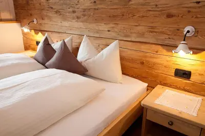 a bedroom with a bed with white sheets and pillows at Tiefentalhof - Urlaub am Bauernhof in Tesido