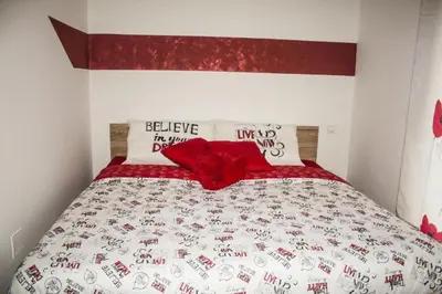 a bed with a red and white comforter and pillows at Apartment BELLA VISTA in Bolzano