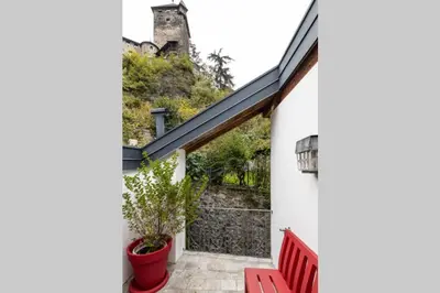 a patio with two red chairs and a building at Zweizimmer-Wohnung mit Schlossblick in Chiusa