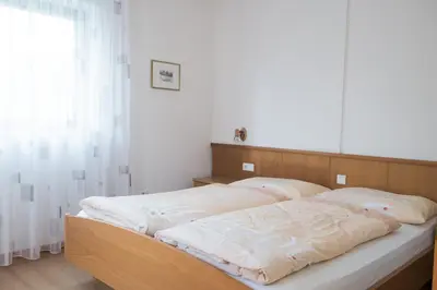 a bedroom with two beds with white sheets and a window at Ferienwohnung Pippohof in Appiano sulla Strada del Vino