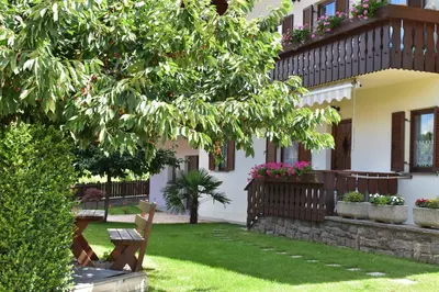 a bench in the yard of a house with flowers at Ferienwohnung Pippohof in Appiano sulla Strada del Vino