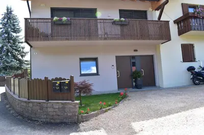 a house with a fence and flowers in front of it at Ferienwohnung Pippohof in Appiano sulla Strada del Vino