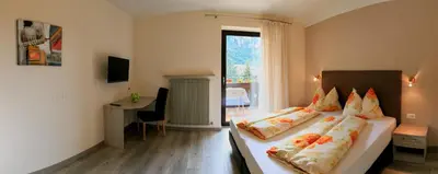 a bedroom with two beds and a desk and a window at Garni Wieterer in Terlano