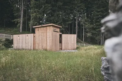 a wooden building in a field with a fence at Tenne Chalets in Racines