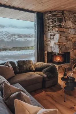 a living room with a couch and a stone fireplace at Tenne Chalets in Racines