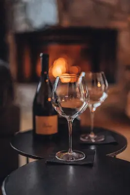 two wine glasses sitting on a table with a bottle of wine at Tenne Chalets in Racines