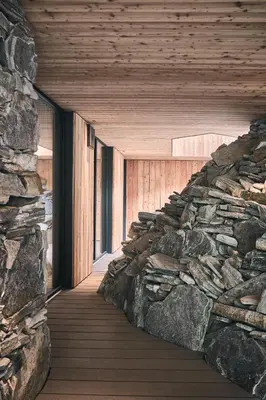 a room with a stone wall and a wooden walkway at Tenne Chalets in Racines
