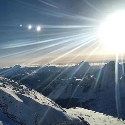 a sun is shining over a snow covered mountain at Monte Pelmo in Alleghe