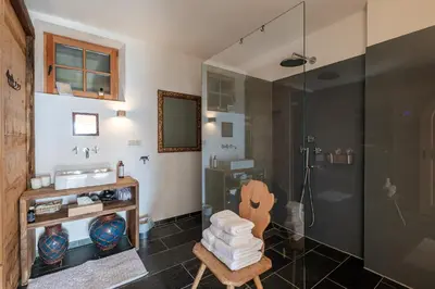 a bathroom with a shower with a chair and a glass shower stall at Haus Sophie in Longomoso