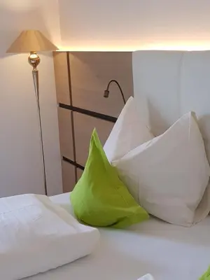 a bed with white pillows and a green pillow at Pension Gartscheid in Lana