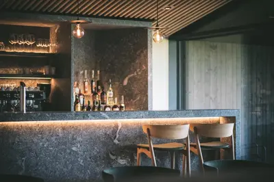 a bar with two stools at a counter with bottles at Hotel Milla Montis in Maranza