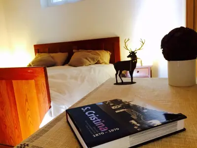 a book on a table next to a bed at La terrazza gardenese in Santa Cristina in Val Gardena