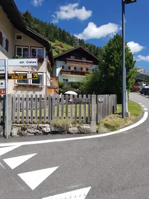 a fence on the side of a road with a house at La terrazza gardenese in Santa Cristina in Val Gardena