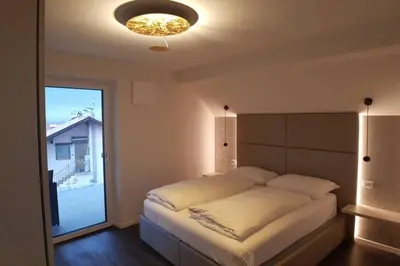 a bedroom with a large bed and a large window at Gardenpark Loft in Ora/Auer