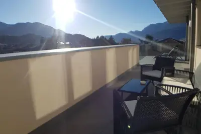 two chairs and a table on a balcony with a view at Gardenpark Loft in Ora/Auer