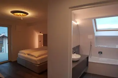 a bedroom with a bed and a sink and a window at Gardenpark Loft in Ora/Auer