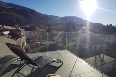 a chair on a balcony with a view of a mountain at Gardenpark Loft in Ora/Auer