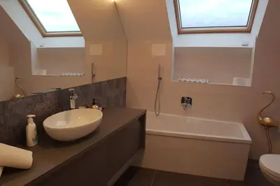 a bathroom with a sink and a tub and a mirror at Gardenpark Loft in Ora/Auer