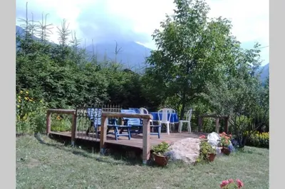 a wooden deck with chairs and a table in a yard at Paola’s Country Home - Vanoi Primiero Trentino in Canale San Bovo