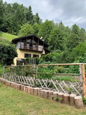 a house on top of a hill with a fence at Paola’s Country Home - Vanoi Primiero Trentino in Canale San Bovo
