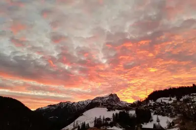 a sunset over a snow covered mountain with a city at La Majon in Colle Santa Lucia