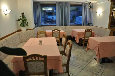 a restaurant with tables and chairs with pink tablecloths at Albergo Dolomiti in Capriana