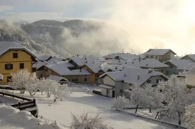 a village covered in snow with mountains in the background at Albergo Dolomiti in Capriana