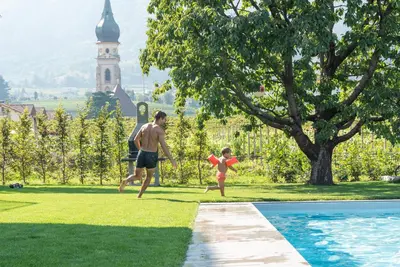 a man and a child playing with a frisbee by a pool at Paulsner Feldhof in Appiano sulla Strada del Vino