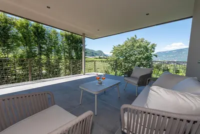 a patio with a couch and chairs and a table at Paulsner Feldhof in Appiano sulla Strada del Vino