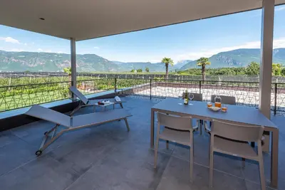 a patio with a table and chairs and mountains at Paulsner Feldhof in Appiano sulla Strada del Vino