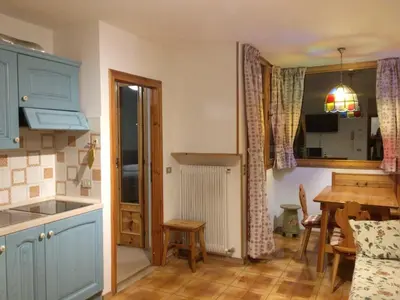 a kitchen with blue cabinets and a table and a dining room at Appartamento Nemo in Alleghe