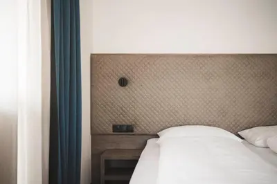 a bedroom with a white bed with a head board at Hotel Schölzhorn Superior in Racines