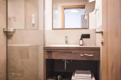 a bathroom with a sink and a mirror and a shower at Hotel Schölzhorn Superior in Racines