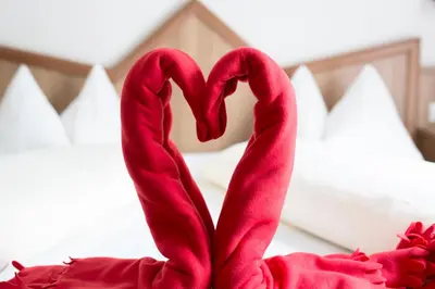 a pair of red swans sitting on a bed at Hotel Maibad in Vipiteno