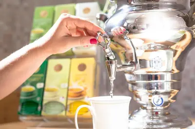 a woman is pouring coffee into a cup at Hotel Maibad in Vipiteno
