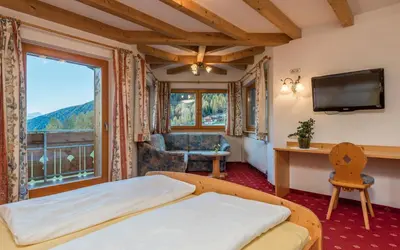a bedroom with a bed and a large window at Hotel Kaserhof in Valles