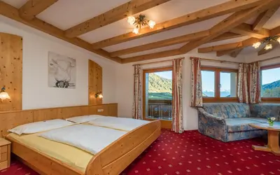 a bedroom with a large bed and a couch at Hotel Kaserhof in Valles