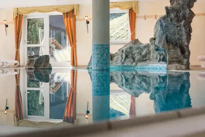 a swimming pool with a rock in the middle of a room at Hotel Kaserhof in Valles